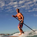 guy rides a wave on paddle board